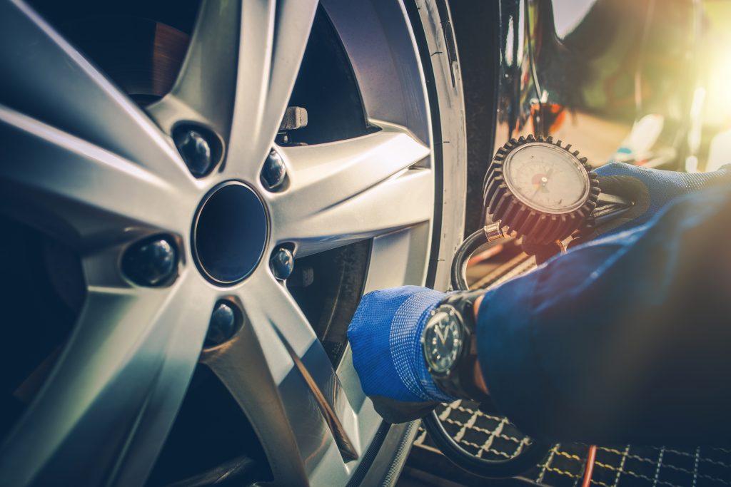 Close-up of car tire and alloy wheel with air pressure gauge nearby